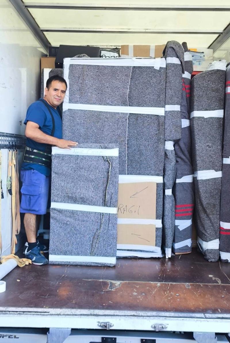 Joe, fundador de CandenMovers, sonríe dentro del camión junto a muebles envueltos en mantas